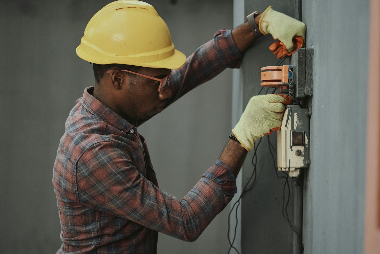 Technician wiring equipment on an exterior wall during a residential heat pump installation