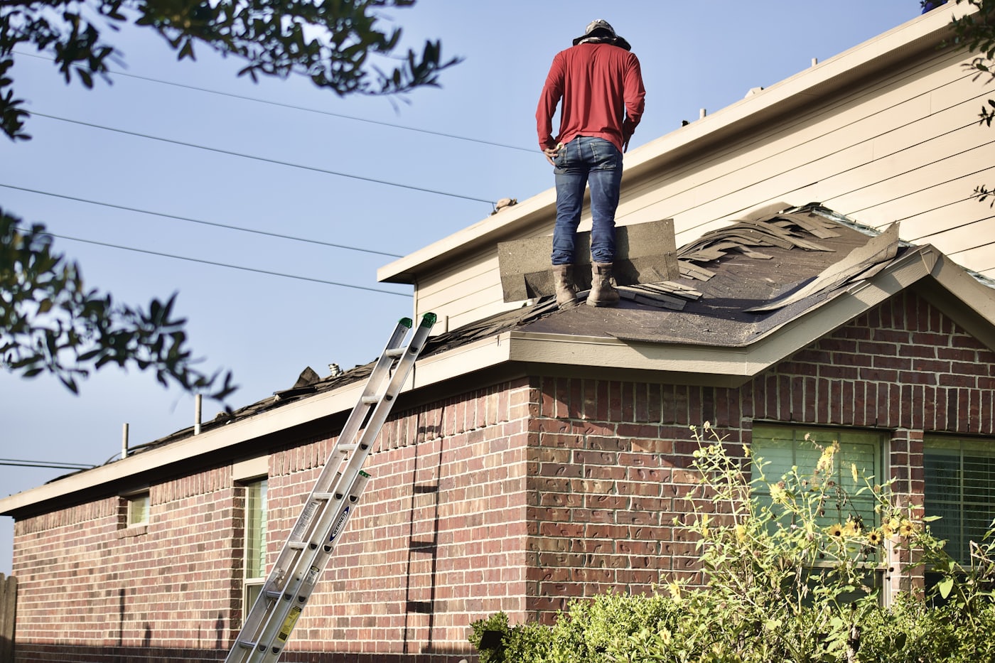 Contractor working on the roof deck of a brick single-family home during an insulation and air-sealing project