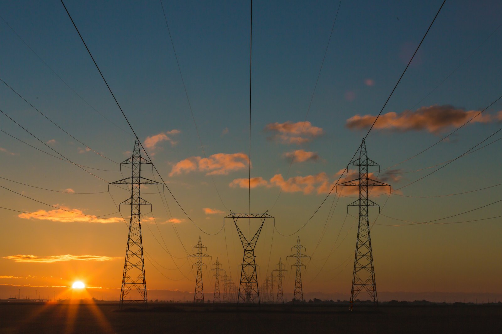 High-voltage transmission lines at sunset — utility rebate programs guide